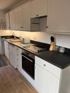 a kitchen with white cabinets and a black counter top at The Old Dairy Steep,Petersfield in Collyers Estate in the South Downs National park in Petersfield