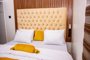 een slaapkamer met een groot bed met gele kussens bij NIFEWAT APARTMENT,Bris suite 1bedroom apartment gym, Netflix,WiFi in Abuja