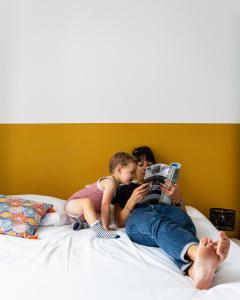 a woman and a child sitting on a bed reading a book at Le Patio - Vallée d'Aspe in Bedous