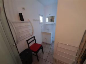 Cette petite chambre comprend une chaise rouge et un mur blanc. dans l'établissement Maisonnée avec une chambre, à Saint-Michel-en-lʼHerm