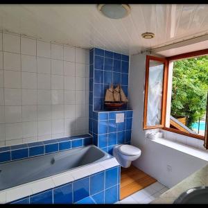 a blue tiled bathroom with a tub and a toilet at Baleine-Les Jardins de Kuz in Bernin