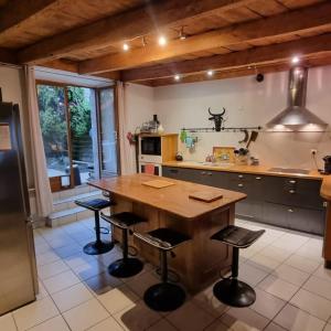 una cocina con mesa de madera y taburetes de bar en Baleine-Les Jardins de Kuz, en Bernin