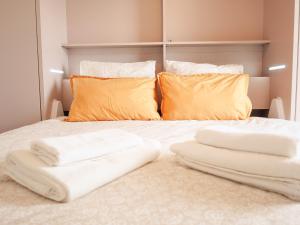 1 cama con 3 toallas blancas y almohadas naranjas en B&B : La Loggia Bastide, en Burdeos