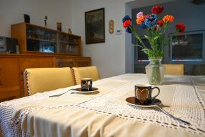 een tafel met twee kopjes en een vaas met bloemen bij Apartment Maca Bled in Bled