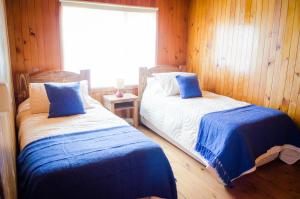 two beds in a room with wooden walls and a window at Casa Pehuen, Cabañas in Villarrica +4 photos