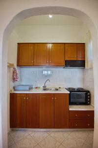 eine Küche mit Holzschränken, einer Spüle und einer Mikrowelle in der Unterkunft Thea Studios in Kalamakia