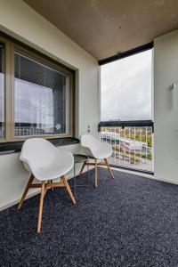 twee witte stoelen in een kamer met twee ramen bij Apartment, SleepWell, Kirstinpuisto in Turku