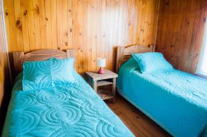 a bedroom with two beds and a table with a lamp at Casa Pehuen, Cabañas in Villarrica