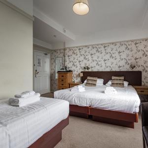 a bedroom with two beds and a dresser at The Castle Of Brecon Hotel, Brecon, Powys in Brecon