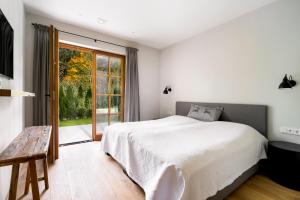 a bedroom with a white bed and a large window at Garten Suite Kirchberg by Alpine Host Helpers in Kirchberg in Tirol