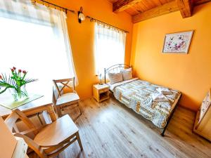 1 dormitorio con paredes de color naranja, 1 cama y 1 mesa en Młyn Wielisław Agroturystyka i Restauracja, en Sędziszowa