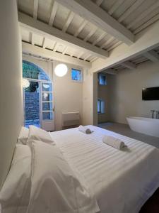 1 dormitorio con 1 cama blanca grande y bañera en Urbino Apartment - Torricini View, en Urbino