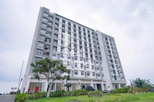 ein großes weißes Gebäude mit einem Baum davor in der Unterkunft RedLiving Apartemen Bogorienze Resort - Skyland Tower A in Bogor