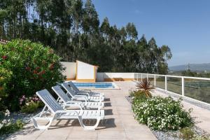 uma fila de espreguiçadeiras sentadas ao lado de uma piscina em Casa Amarela - Countryside Villa by LovelyStay em Alcobaça