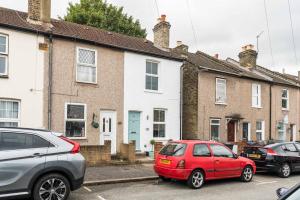 a red car parked in front of a row of houses at Dressed To Impress 2 bed house in Heart of Croydon Photo ID Required in Croydon