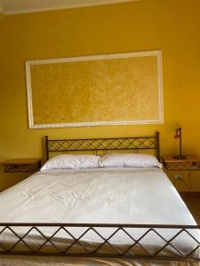 a bed in a bedroom with a yellow wall at B&B Lucius in Pompei