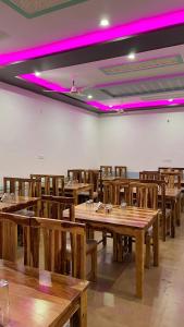 een restaurant met houten tafels en stoelen met paarse verlichting bij NK Desert Camp Jaisalmer in Sām