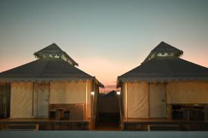 twee yurt gebouwen met de zonsondergang op de achtergrond bij NK Desert Camp Jaisalmer in Sām