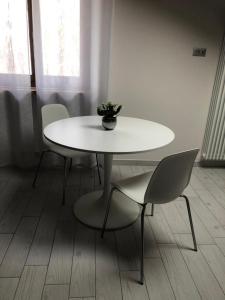 une table et des chaises blanches avec un vase. dans l'établissement La Cinciallegra, à Govone