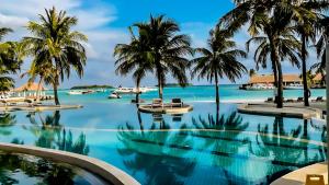 a swimming pool with palm trees and a beach at Holiday Inn Resort Kandooma Maldives - Kids Stay & Eat Free and DIVE FREE for Certified Divers for a minimum 3 nights stay in Guraidhoo