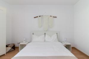 a white bedroom with a white bed and two tables at Casa Angelica in Praia do Carvoeiro