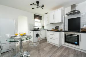 a white kitchen with a glass table with chairs and a tv at Dressed to impress 2 bed house in Heart of Croydon ID Required in Croydon