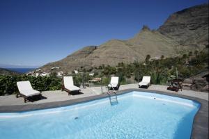 a swimming pool with chairs and a mountain at Casa rural en el Risco de Agaete A in Agaete