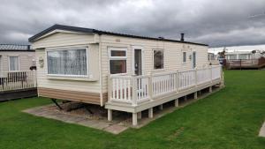 a white house with a porch on a yard at 6 Berth heated on The Chase (Albany II) in Skegness