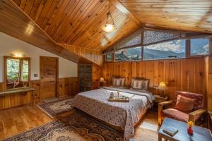 een slaapkamer met een bed in een kamer met houten wanden bij StayVista at Himalayan Retreat in Manāli