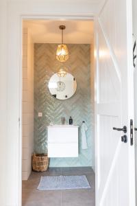 een badkamer met een witte wastafel en een spiegel bij de Zuiderstolp in Zuidermeer