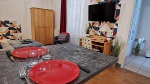 una sala de estar con una mesa con platos rojos. en Le Lucerne, entre thermes et centre ville-lamaisondefrancois03, en Vichy