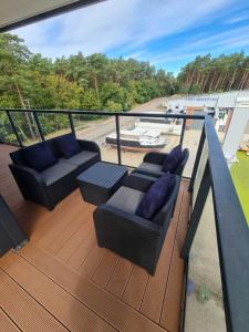 balkon z 2 kanapami i krzesłami na tarasie w obiekcie Apartament CARO w mieście Mrzeżyno