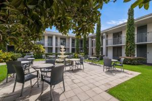 Clarion Inn & Suites Across From Universal Orlando Resort في أورلاندو: فناء فيه طاولات وكراسي امام مبنى