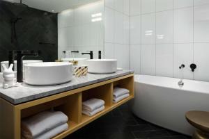 a bathroom with two sinks and a bath tub at QT Wellington in Wellington