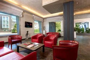 サン・ドナ・ディ・ピアーヴェにあるベスト ウェスタン パーク ホテル コンチネンタルの赤い椅子とテーブルが備わる待合室