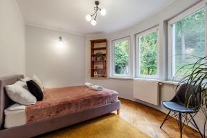 a bedroom with a bed and a chair and windows at Beach House Escape in Gdynia