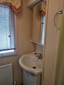 a bathroom with a white sink and a window at Quite 3 Bedroom Static Caravan in Sidcup