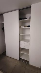 an open closet with white doors and shelves at Studio confort avec jardinet in Montjoly