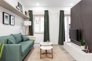 uma sala de estar com um sofá verde e uma televisão em Studios Terra & Mar em Lisboa