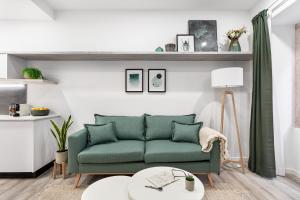uma sala de estar com um sofá verde e mesas em Studios Terra & Mar em Lisboa