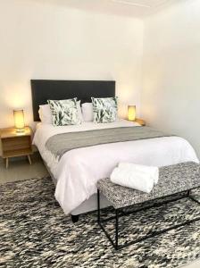 a bedroom with a large bed with a table and two lamps at Angazi Guesthouse Unit 3 - Modern 2 Bedroom Apartment with Pool in Hillcrest