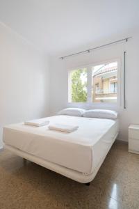 a white bedroom with a large bed and a window at Homenfun Barcelona Park Güell in Barcelona