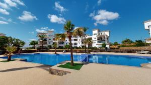 a swimming pool with palm trees in front of a building at Casa Atlantico A-A Murcia Holiday Rentals Property in Sucina