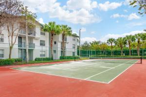 - un court de tennis en face d'un bâtiment avec des palmiers dans l'établissement Bright and Modern Apartments at Palm Trace Landings in South Florida, à Davie