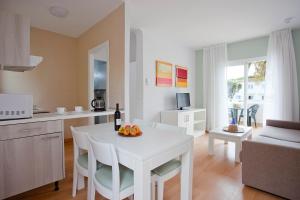 cocina y sala de estar con mesa blanca y sillas en Apartamentos Vista Alegre Mallorca en Porto Cristo