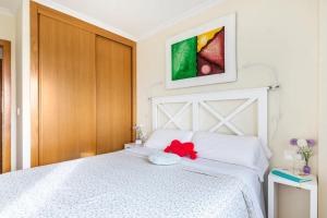 Un dormitorio con una cama blanca con una flor roja. en APT SOLEADO y SILENCIOSO - GARAJE- A 17 min andando del centro de Pontevedra, en Pontevedra
