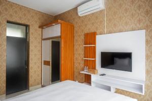 Schlafzimmer mit einem Bett, einem TV und einem Spiegel in der Unterkunft The Lavana Greenkhaza Villa Jogja in Yogyakarta