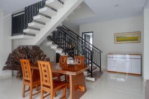 ein Esszimmer mit Tisch und Stühlen und einer Treppe in der Unterkunft The Lavana Greenkhaza Villa Jogja in Yogyakarta