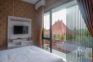 ein Schlafzimmer mit einem Bett und einem großen Fenster in der Unterkunft The Lavana Greenkhaza Villa Jogja in Yogyakarta