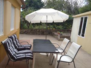 una mesa y sillas con una sombrilla en el patio en Casita con terreno a 10 minutos del centro de Vigo en Moaña